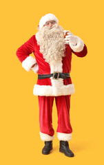 Santa Claus with glass of beer on yellow background