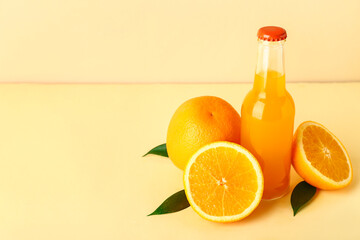 Bottle of fresh orange juice and leaves on color background