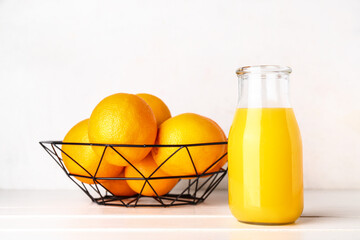 Bottle of fresh orange juice on white wooden table