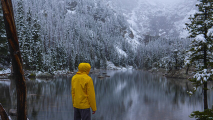 Person wearing jacket standing along a lake during a snowstorm in the Rocky Mountains of Colorado, USA