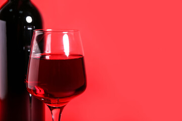 Bottle and glass of wine on red background