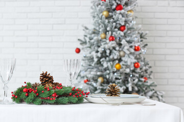 Christmas table setting with fir cones and wreath in room, closeup