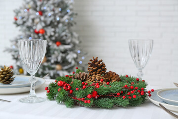 Christmas table setting with fir cones and wreath in room, closeup