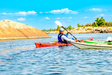Naklejka premium young man paddling on a multiday sea kayak expedition on georgian bay ontario room for text