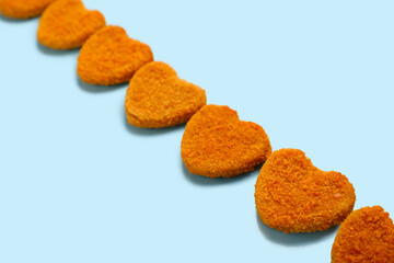 Tasty nuggets in shape of heart on blue background. Valentine's Day celebration