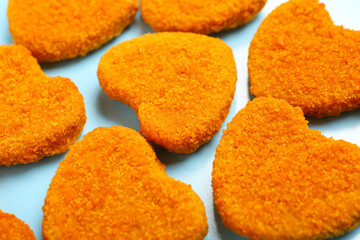 Tasty nuggets in shape of heart on blue background. Valentine's Day celebration
