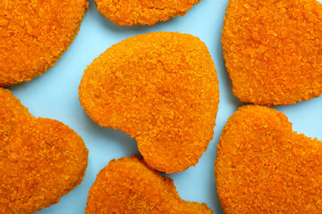 Tasty nuggets in shape of heart on blue background. Valentine's Day celebration