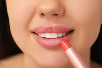 Young woman with beautiful lips applying lipstick, closeup