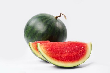 Whole watermelon and seeded slices seen front and top on a white background. Watermelon slices are red, seedy and juicy.