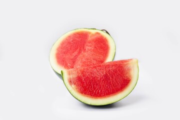 Whole watermelon and seeded slices seen front and top on a white background. Watermelon slices are red, seedy and juicy.