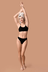 Obraz premium Beautiful young happy woman with towel after shower on brown background