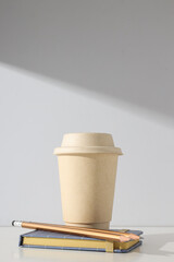 A paper cup with a lid on a light background