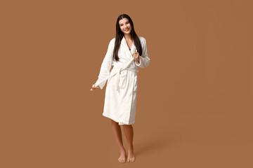 Beautiful young happy woman in bathrobe after shower on brown background