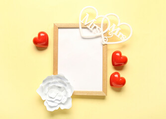Composition with blank frame and hearts for Valentine's Day on beige background