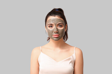 Young woman with facial mask on grey background