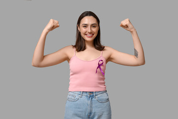 Strong young woman with purple ribbon on grey background. Pancreatic cancer awareness concept
