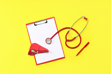 Clipboard, paper liver and stethoscope on yellow background