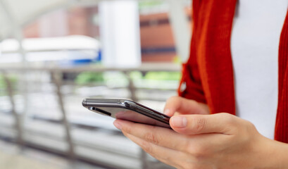 Woman holding smartphone while walking in the urban city. The concept of using the phone is essential in everyday life.