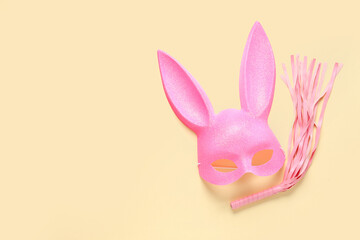 Pink bunny mask with whip on yellow background