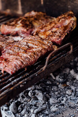 Roasted meat on the grill. Barbeque, bbq meat cooking. Traditional Asado of Argentina, Paraguay and Uruguay. Vertical format.