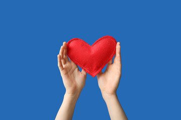 Female hands with red heart on blue background, closeup. Valentine's Day celebration