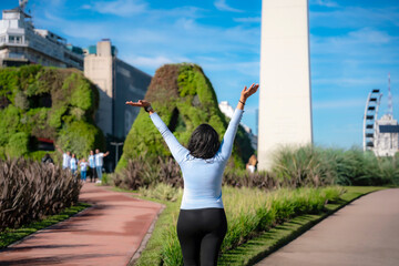 Unrecognizable young Latina woman smiling in front of the iconic Obelisk in Buenos Aires,...