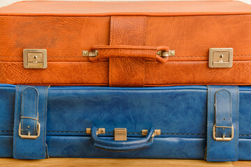 Brown and blue retro leather suitcases on floor in room. Closeup