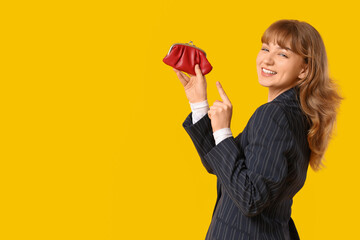 Beautiful young woman pointing at red purse on yellow background