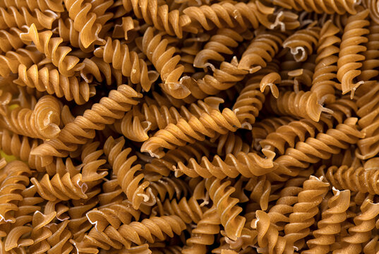 Detailed close-up of uncooked whole wheat fusilli pasta, showcasing texture and spiral shapes. - Powered by Adobe