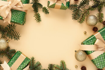 Frame made of gifts, Christmas balls and fir tree branches on beige background, closeup