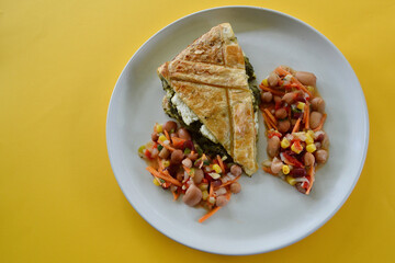 Yaya Spanikopita ( Greek spinach pie ) with mixed bean salad on a plate.