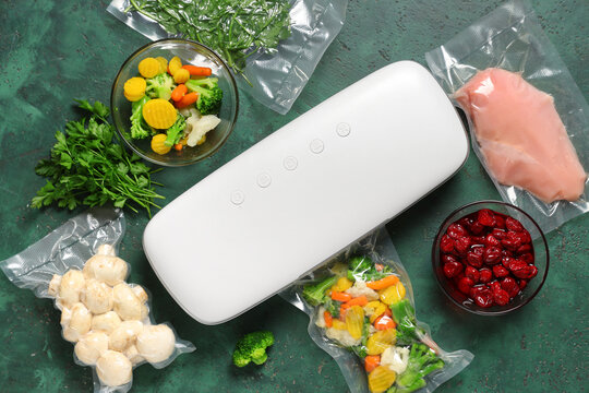 Vacuum sealer machine with food in packs on green grunge background