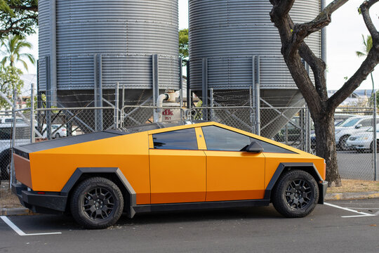 Honolulu, HI, USA - Aug 28, 2024: A new Tesla Cybertruck in orange color is seen in a public parking lot in Honolulu, Hawaii. Cybertruck is a battery electric pickup truck built by Tesla, Inc.