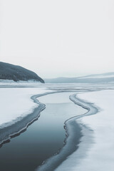 Obraz premium Frozen landscape with a winding river through the snow, under a soft gray sky, creating a calm and minimalist winter vibe