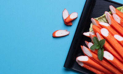Crab sticks on a black plate ,blue background.top view © showcake