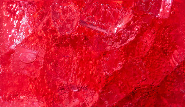 Red carbonated drink with ice,strawberry soda and ice splashing fizzing or floating up to top