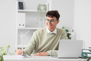 Male engineer with wind turbine model sitting at table in office
