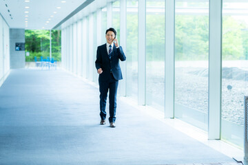 オフィスの廊下でスマホを操作するビジネスマン