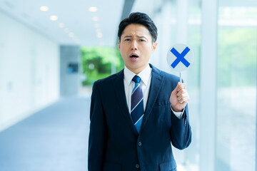 バツ印のプレートを持つビジネスマン