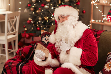 Santa Claus with letters sitting at home on Christmas eve