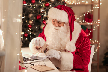 Santa Claus with letters at home on Christmas eve