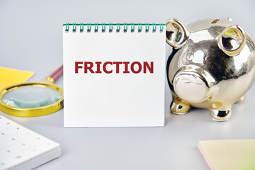 Friction concept. Friction word on a white notepad with business accessories close-up