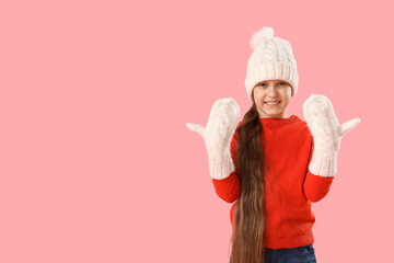 Cute happy little girl in warm Christmas clothes on pink background