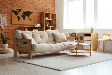 World map on brick wall, sofa and table in interior of stylish living room