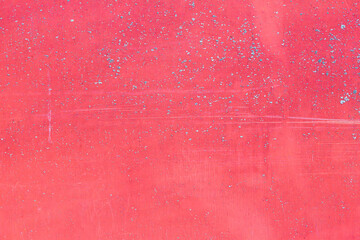 The texture of a pink surface with splashes of blue. A wall or other surface is scuffed and lightly...