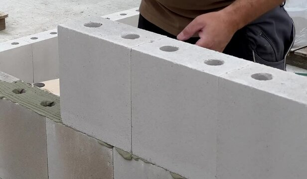 Close up of a construction worker bricklayer laying a wall with white block stones