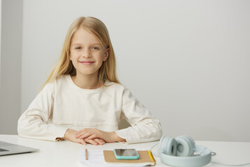 Teenage girl smiling and learning at home elearning with a laptop She is sitting at a modern desk, typing on her notebook, fully immersed in an online game for education The girl showcases her