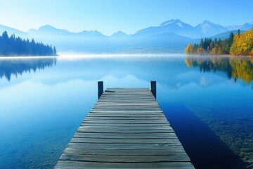Fototapeta premium Scenic view of a dock extending into a calm lake surrounded by mountains.