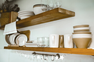 Wooden shelf with Glass, coffee cup, plate, bowl various cookware and decoration in kitchen. Hanging storage. Organization kitchen room concept