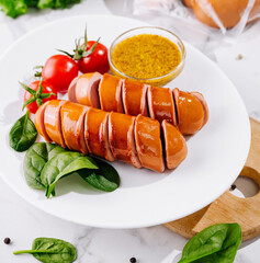 Sliced sausages on white plate with mustard greens and tomatoes